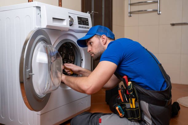 Working man plumber repairs a washing machine in home. Washing machine installation or repair. plumber connecting appliance.